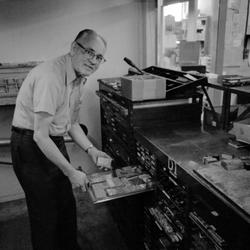 Walter Ellis bent over a drawer containing rubber stamps at the Ellis Rubber Stamp Co., 1973