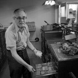 Walter Ellis bent over a drawer containing rubber stamps at the Ellis Rubber Stamp Co., 1973 (2nd)