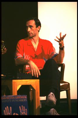 David Van Tieghem, seated, talking onstage during Speaking of Music (1987)