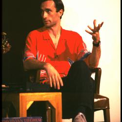 David Van Tieghem, seated, talking onstage during Speaking of Music (1987)