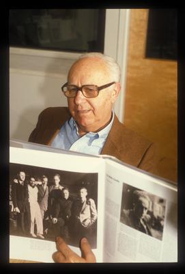 David Raksin, seated at a table displaying a book at the Exploratorium