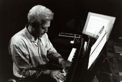Chris Brown, half length portrait, seated, facing right & slightly down, playing the piano, San Francisco, (2001)