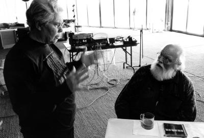 Pauline Oliveros, standing & Lou Harrison, seated, looking at each other, Woodside CA, (2002)