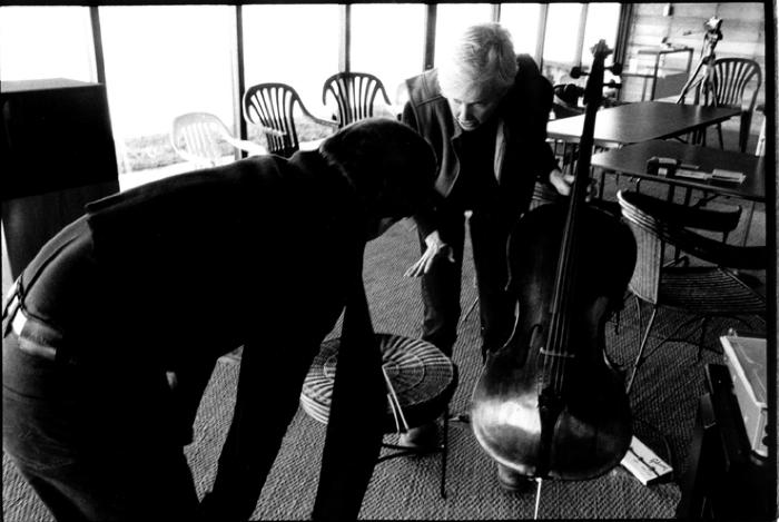 Stefan Hussong, bent over with back to camera, and Joan Jeanrenaud, bent over, holding cello, facing down (cropped image)