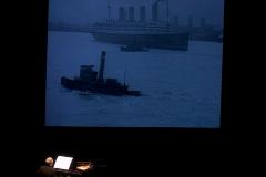 Michael Nyman, seated at piano, back to camera, with an image of ships projected above him, horizontal ver., San Francisco CA., (2005)