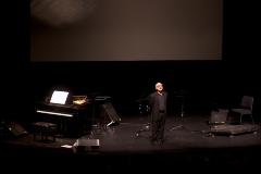 Michael Nyman, standing on stage next to piano, facing slightly right, San Francisco CA., (2005)