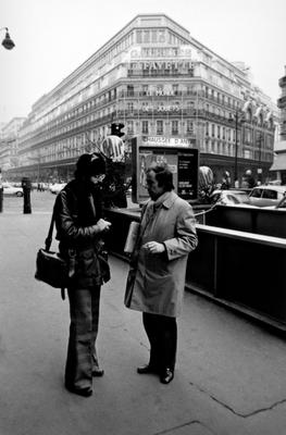 Full length portrait of Charles Amirkhanian talking with Bernard Heidsieck on a Parisian street, by the Chausée D'Antin metro, 1973