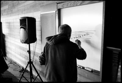 Paweł Mykietyn, head and shoulders portrait, back to camera, writing on whiteboard, Woodside CA., vs 2 (2010)