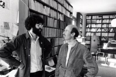 Charles Amirkhanian & Han Reiziger, half length portrait, facing each other, in KPFA office, Berkeley CA, 1975