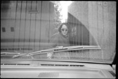 Yoko Sugiura Nancarrow, standing in front of a gate, as seen through the windshield of a car, Mexico, 1990
