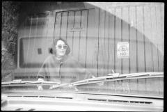 Yoko Sugiura Nancarrow, standing in front of a gate, as seen through the windshield of a car,  vs. 2, Mexico, 1990
