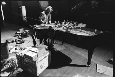 Trimpin, full length portrait, standing over and modifying piano, ver. 1, 1993