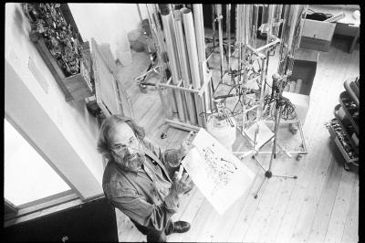 Trimpin, full length portrait, standing in his studio, holding a diagram, as seen from above, Seattle 