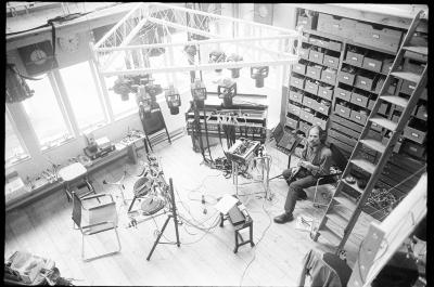 Trimpin, full length portrait, seated in his studio, facing slightly left, as seen from above, ver. 1, Seattle