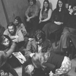 A group of people sitting in the KPFA studio waiting to participate in a performance of Annea Lockwood's "Music for Multiple Hummers" (1972)