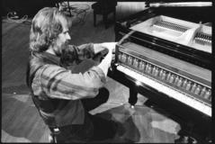 Trimpin, kneeling, making adjustments to modified piano, 1993 