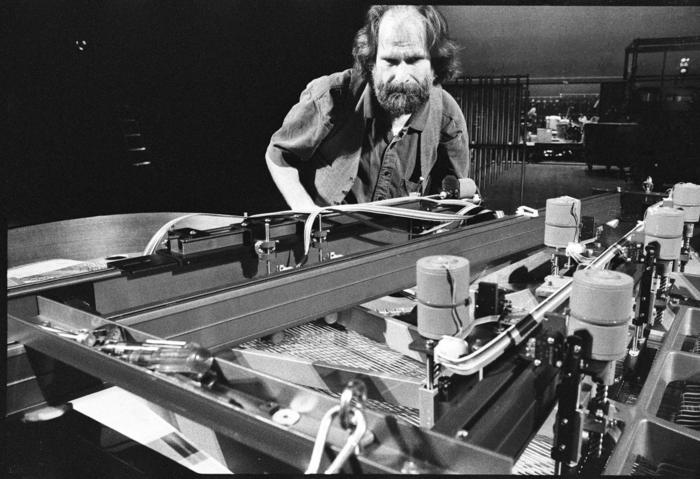 Trimpin, half length portrait, bending over modified piano, 1993