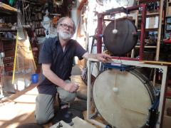 Trimpin, kneeling next to drum parts of the Nancarrow Percussion Orchestra, vs. 3, Seattle (2012)
