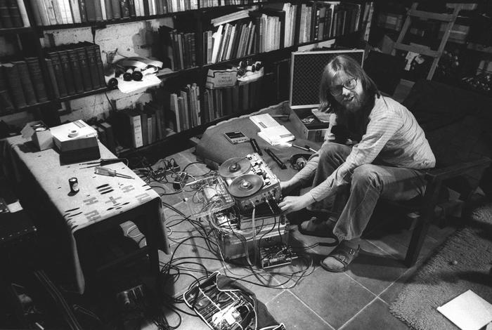 Robert Shumaker, full length portrait, seated with head turned toward camera, working with a tape recorder, Mexico City, (1977)