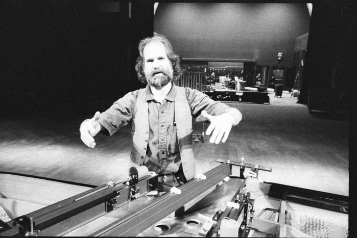 Trimpin, half length portrait, standing behind piano, San Francisco, 1993