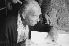 Ernst Krenek, seated, head and shoulders portrait, pointing over page of a score (1985)