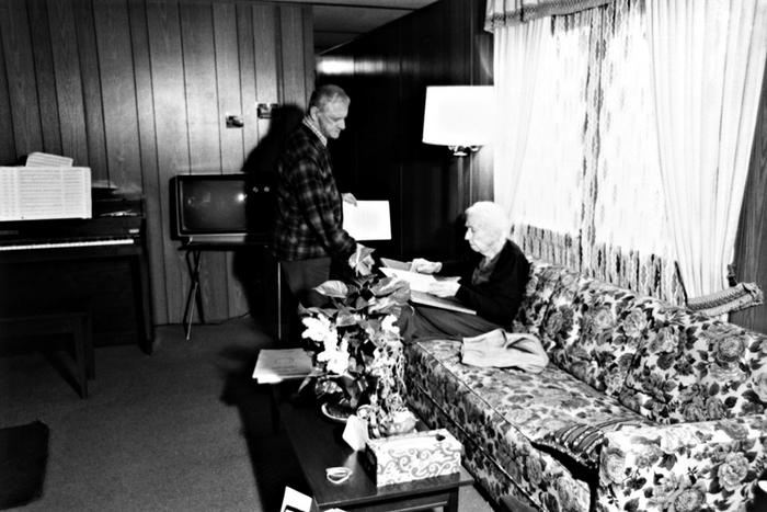 Leo Ornstein standing next to his seated wife Pauline, who is examining a document, Brownsville TX, 1981