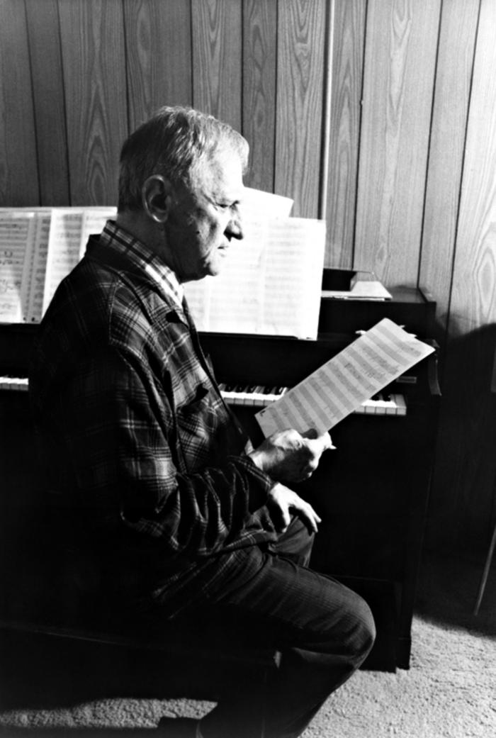 Leo Ornstein, seated on piano bench, facing right, looking at musical score, Brownsville TX, 1981