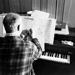 Leo Ornstein, seated at a piano, marking a score, Brownsville TX, 1981