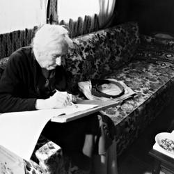 Pauline Ornstein seated, examining a document, Brownsville TX, 1981