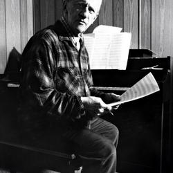 Leo Ornstein, seated at his piano, facing forward and holding a musical score, Brownsville TX, 1981