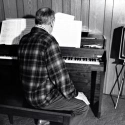 Leo Ornstein, seated at his piano with his back to the camera, Brownsville TX, 1981