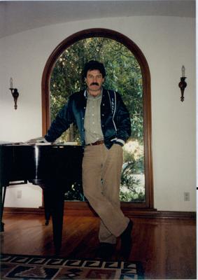 John White, standing, leaning against his piano, Los Angeles, 1983
