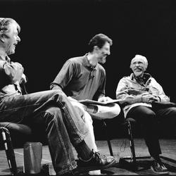 Full-length view of John Cage, Charles Amirkhanian, and Conlon Nancarrow seated on stage in Telluride, CO. (1989)