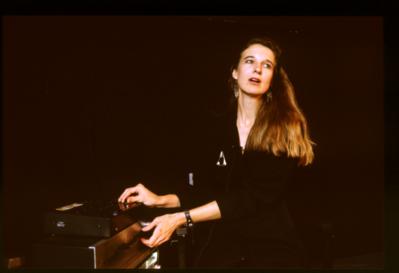 Half length portrait of Susan Stone onstage mixing the output of a tape deck during Speaking of Music at the Exploratorium (1991)