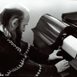 Rex Lawson, head and shoulders portrait, facing down and to the right, adjusting a pianola roll, (1995)