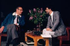 Full length portrait of Mauricio Kagel and Charles Amirkhanian, seated, facing each other on stage during Speaking of Music at the Exploratorium in San Francisco (1988)