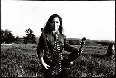 Mari Kimura, three quarter length portrait, kneeling in field holding her violins, facing forward, Woodside CA, (1995)