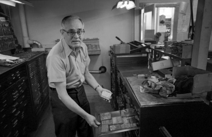 Walter Ellis bent over a drawer containing rubber stamps at the Ellis Rubber Stamp Co., 1973 (2nd)