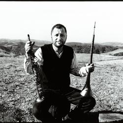 Hafez Modirzadeh, full length portrait, seated and holding saxophone, Woodside CA, (1997)