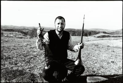 Hafez Modirzadeh, full length portrait, seated and holding saxophone, Woodside CA, (1997)
