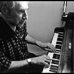 Frederic Rzewski, half length portrait, playing the piano, as seen from the side, 1996 (cropped image)