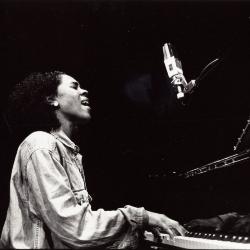 Errollyn Wallen, half length portrait, facing right, seated and playing the piano, San Francisco 1999 (cropped image)