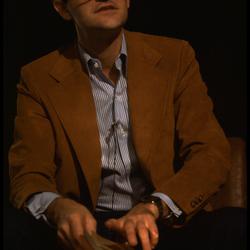 David Rosenboom, seated and speaking onstage during Speaking of Music at the Exploratorium