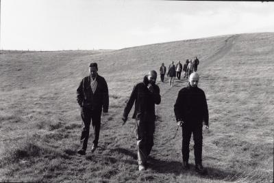 Peter Garland, Paul D. Miller, and Robin Rimbaud walking, along with other OM 6 artists, Woodside, 2000 (cropped image)