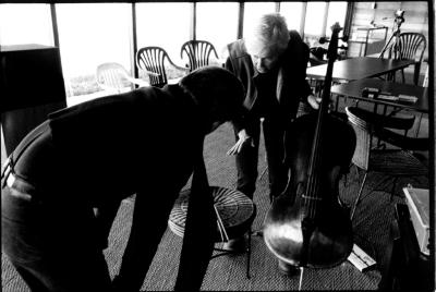 Stefan Hussong, bent over with back to camera, and Joan Jeanrenaud, bent over, holding cello, facing down (cropped image)