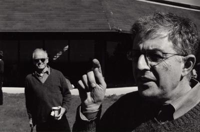 Head and shoulders portrait of Charles Amirkhanian, pointing, while Jim Newman smiles in the background, Woodside CA, (2004)