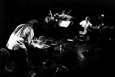 Daniel Bernard Roumain performing onstage with Del Sol String Quartet and DJ Scientific during OM 11, San Francisco, CA (2005)