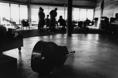 A double bass in the foreground with a group of people silhouetted against the windows in the background, Woodside CA, 2006