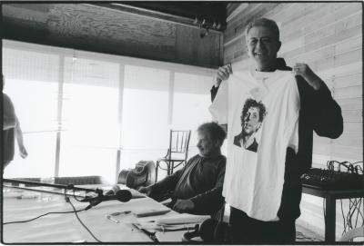 Charles Amirkhanian holding up a shirt with an image of Philip Glass , Woodside CA, 2008
