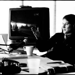 Lisa Bielawa, half length portrait, facing left, seated at table with microphone, giving a presentation, Woodside CA., (2010)